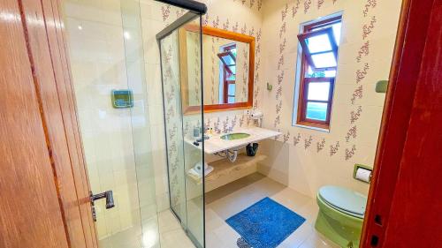 a bathroom with a shower and a toilet and a sink at Pousada Hortelã Village in Campos do Jordão
