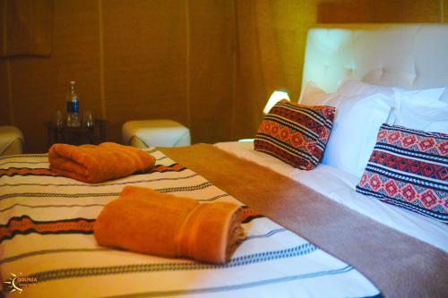 two beds in a hotel room with towels on them at Dounia Luxury Camp in Merzouga