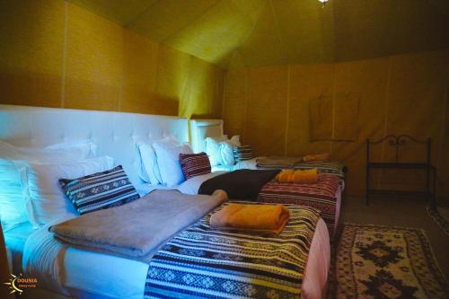 a room with two beds with blankets and pillows at Dounia Luxury Camp in Merzouga