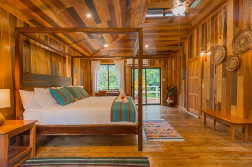 a bedroom with a bed in a room with wooden walls at Jaguar Creek in Good Living Camp
