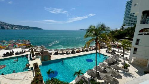 a view of a resort with a swimming pool and the ocean at Suites Omega Torres Gemelas in Acapulco