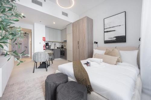 a bedroom with a large white bed and a kitchen at Free housekeeping visits during your stay - StayShort - Sports City Studio sleeps 2 with Swimming Pool in Dubai
