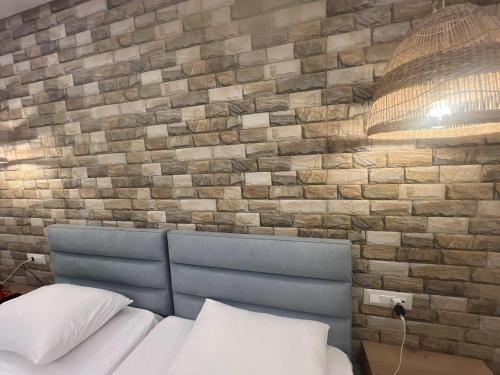 a bed with a blue headboard and a brick wall at Dolphin Hotel Apartments in Karpathos Town