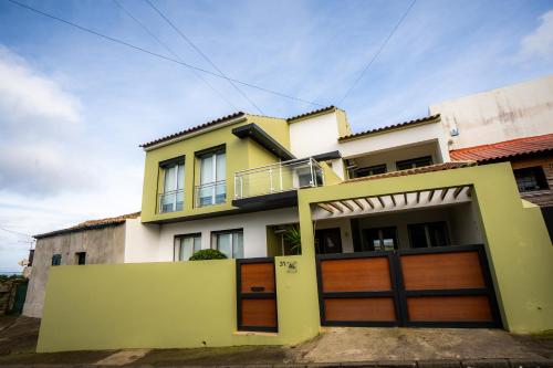 a yellow and white house with wooden garage doors at Azores Mountain View in Ribeira Grande