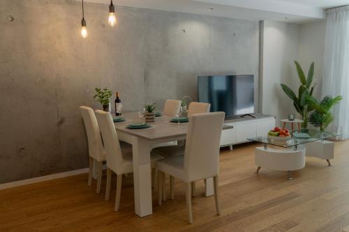 a dining room with a table and chairs and a television at Casa do Sol e Mar in Vila Nova de Gaia