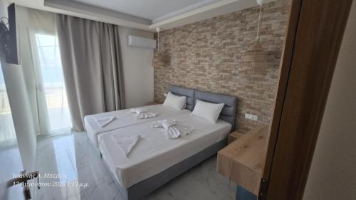 a bedroom with a bed with white sheets and a brick wall at Dolphin Hotel Apartments in Karpathos Town