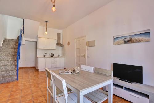 Una cocina y un comedor con una mesa y un televisor. en Casa Marinera El Cotillo duplex for 2-4 persons, en Cotillo