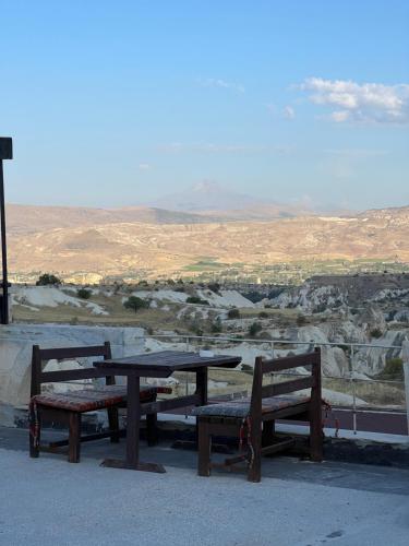 a picnic table and benches with a view of the desert at Tatlı Kaya Otel in Urgup