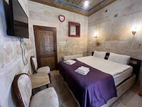 a bedroom with a bed and a tv and chairs at Tatlı Kaya Otel in Urgup