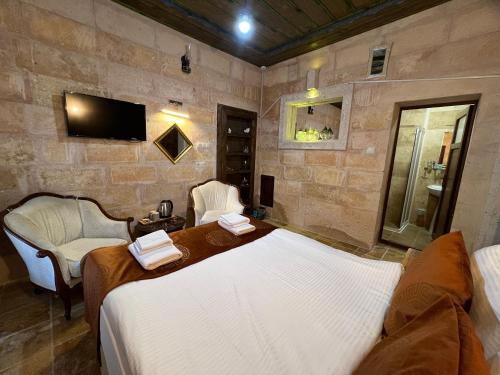a bedroom with a bed and two chairs and a tv at Tatlı Kaya Otel in Urgup