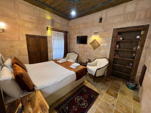 a bedroom with a bed and a chair in a room at Tatlı Kaya Otel in Urgup