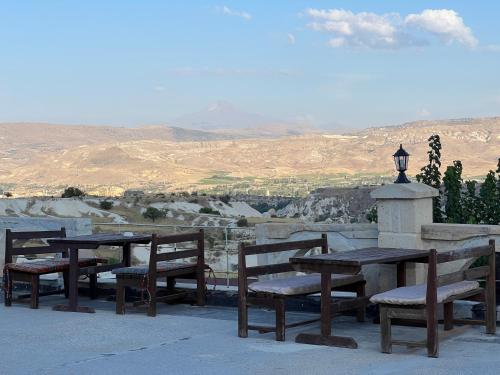 a group of wooden tables and chairs with a view at Tatlı Kaya Otel in Urgup