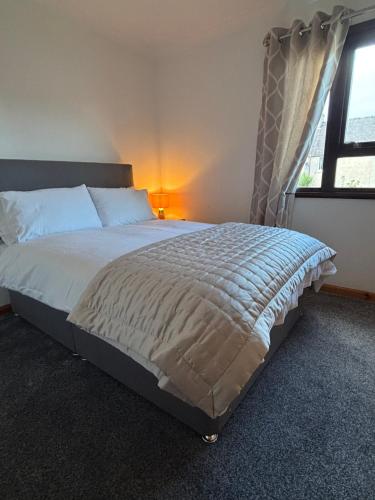 a large bed in a bedroom with a window at Hebridean Holiday House in Stornoway