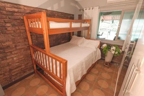a bedroom with a bunk bed and a brick wall at Casa com os pés no mar em Iriri ES in Anchieta