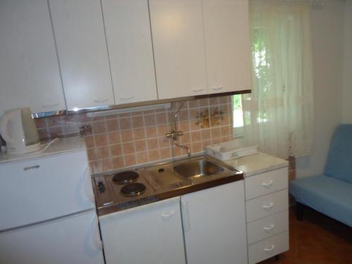 a kitchen with white cabinets and a sink at Omiš apartment on the beach in Omiš