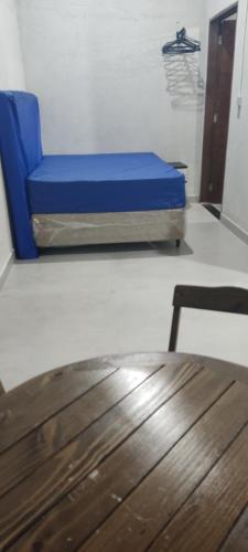 a blue bed in a room with a wooden table at Casa de praia in Ubatuba
