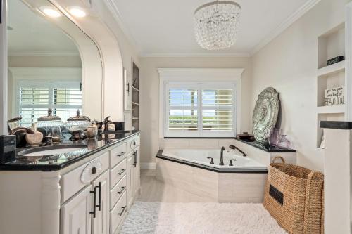 Un baño blanco con bañera y lavabo. en Luxury Riverfront Oasis Dock Pool & Walk 2 Beach, en Port Orange