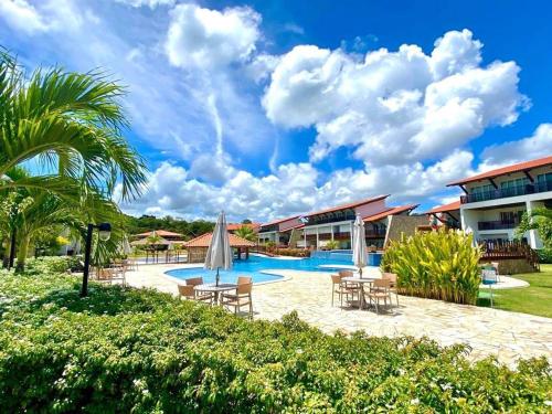 a resort with a swimming pool with tables and chairs at Casa de Praia em Carneiros in Tamandaré
