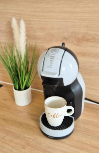 a coffee maker sitting on a table next to a plant at Studio cosy et moderne - Proche Paris et Disney in Gretz-Armainvilliers