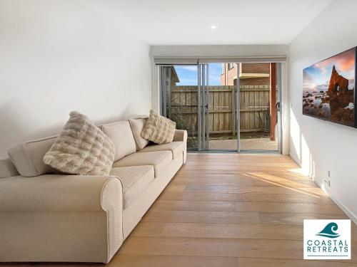 a living room with a couch and a sliding glass door at Hamptons Retreat by the Bay - Cowes Coastal Escape in Cowes