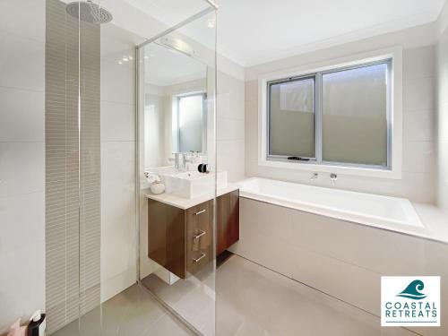a white bathroom with a tub and a sink at Hamptons Retreat by the Bay - Cowes Coastal Escape in Cowes