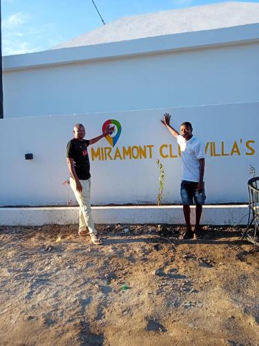 two men are standing in front of a wall at Miramont Club Villas in Nungwi