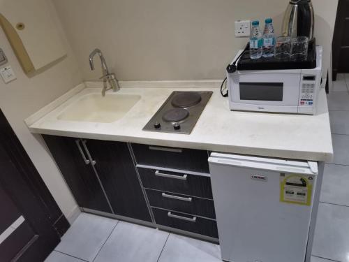 a kitchen with a sink and a microwave at شقق شذا للشقق المخدومة-درجة التصنيف-اقتصادي in Jeddah