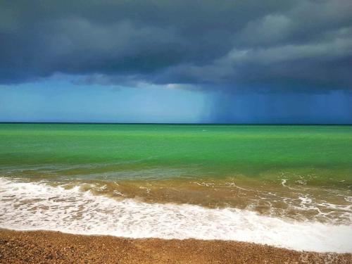 a green ocean with a stormy sky and a beach at 7 person holiday home in Fjerritslev-By Traum in Fjerritslev