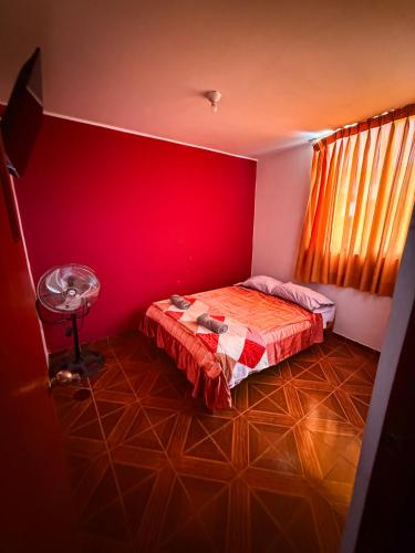 a red room with a bed and a fan at Hospedaje Arco Real in Ica