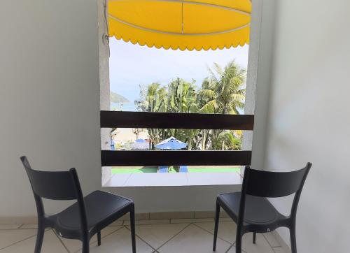 two chairs and a window with a view of a pool at Hotel Porto Di Mare in Ubatuba