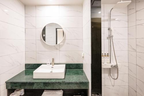 a white bathroom with a sink and a shower at 호텔 시그니처 in Yangsan