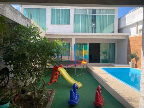 a backyard with a pool with a slide and a playground at Jesaluguel-de-casa in Cabo Frio