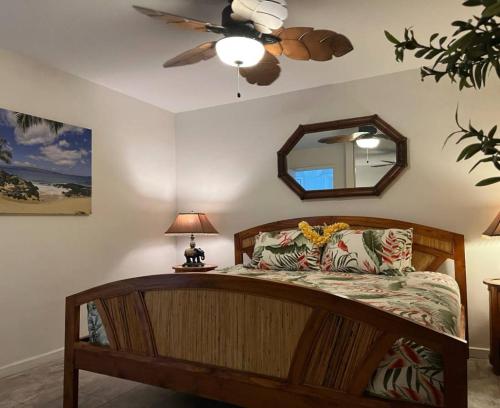 a bedroom with a bed with a ceiling fan and a mirror at Island Surf in Kihei