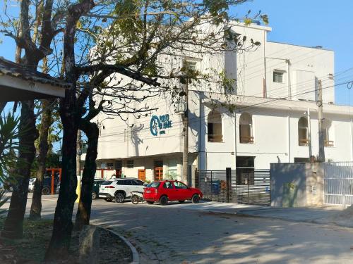 a white building with cars parked in front of it at Hotel Porto Di Mare in Ubatuba