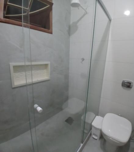 a bathroom with a toilet and a glass shower at Nossa Casa com Piscina in Guarapari