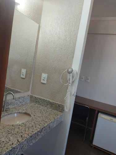 a bathroom with a sink and a hair dryer at Hotel Zé Maria in Pouso Alegre