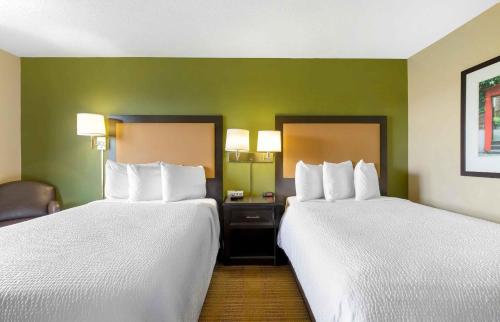 two beds in a hotel room with green walls at Extended Stay America Suites - Raleigh - Midtown in Raleigh