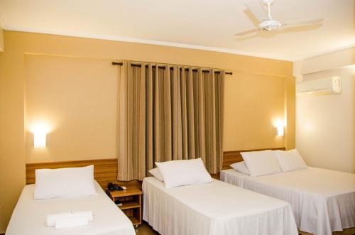a room with two beds and a ceiling fan at Hotel Zé Maria in Pouso Alegre