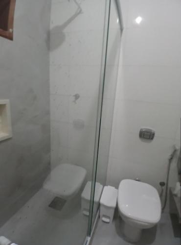 a white bathroom with a toilet and a shower at Nossa Casa com Piscina in Guarapari
