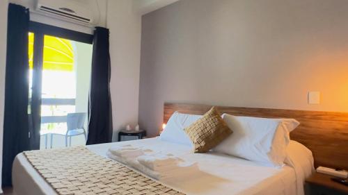 a bedroom with a bed with white sheets and a window at Hotel Porto Di Mare in Ubatuba