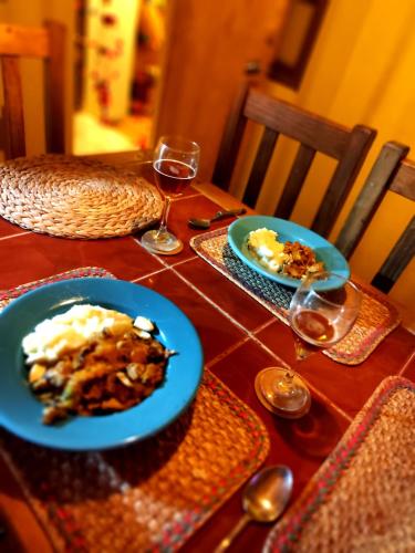 a table with two plates of food and glasses of wine at El KINTU WASI in Vicuña