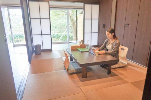 a woman sitting at a table with a laptop at ATAMI SPRING TERRACE HOTEL in Atami