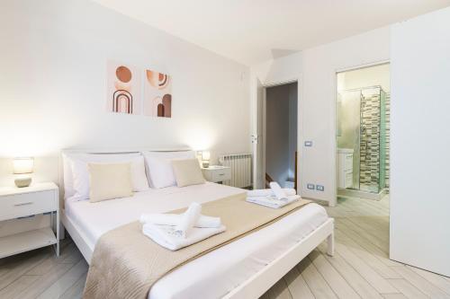 a white bedroom with a large bed with two towels at Ganga House - Mini Loft Moderno-Free Parking in Lastra a Signa
