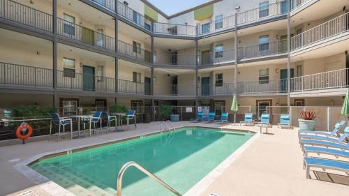 Una piscina frente a un edificio con sillas y un hotel. en Spacious Near ASU Sloan Pk Gym Parking Pool WD, en Tempe