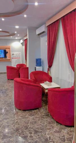 a waiting room with red chairs and a table at شقق قصر اريج لشقق المخدومة in Quai