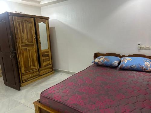 Un dormitorio con una cama y un armario de madera. en Appartement meublé, en Lomé