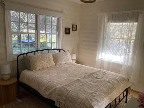 a bedroom with a bed and two windows at Lavender Cottage in Sofala