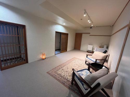 an empty living room with two chairs and a table at Snowfox Nozawa in Nozawa Onsen