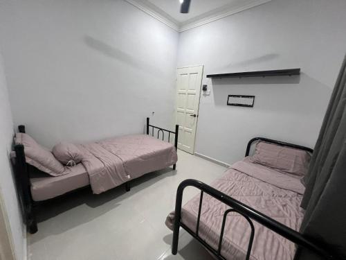 two beds in a room with white walls at Casa De Harmoni in Pasir Puteh