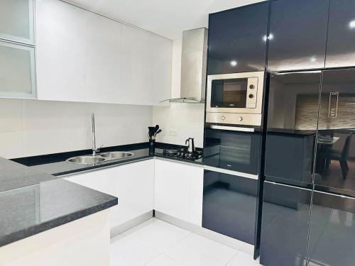 a white kitchen with a microwave and a refrigerator at Levy-Cardoso Apartment in Praia